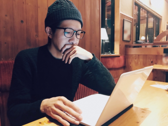 カフェでパソコン作業をするメガネの男性