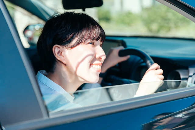 車の運転席に座り窓を開けて外を見る女性