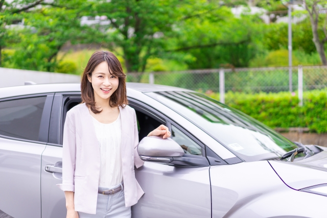 グレーの車の前にいる女性